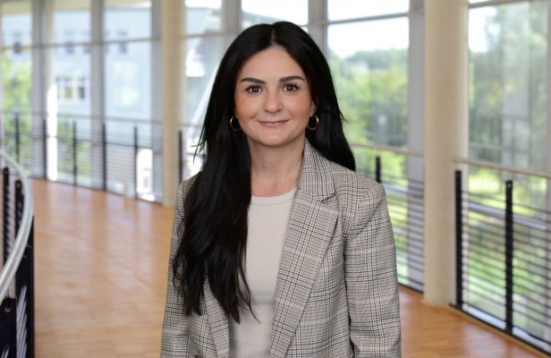 Porträtfoto: Elina Vartanova im audimax. Sie trägt die langen Haare offen und einen grauen Blazer über einem hellen Oberteil.