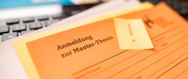 Ein Anmeldeformular für eine Masterarbeit mit verschwommenen Hintergrund und einem Post-it mit einem Ausrufezeichen auf diesem.